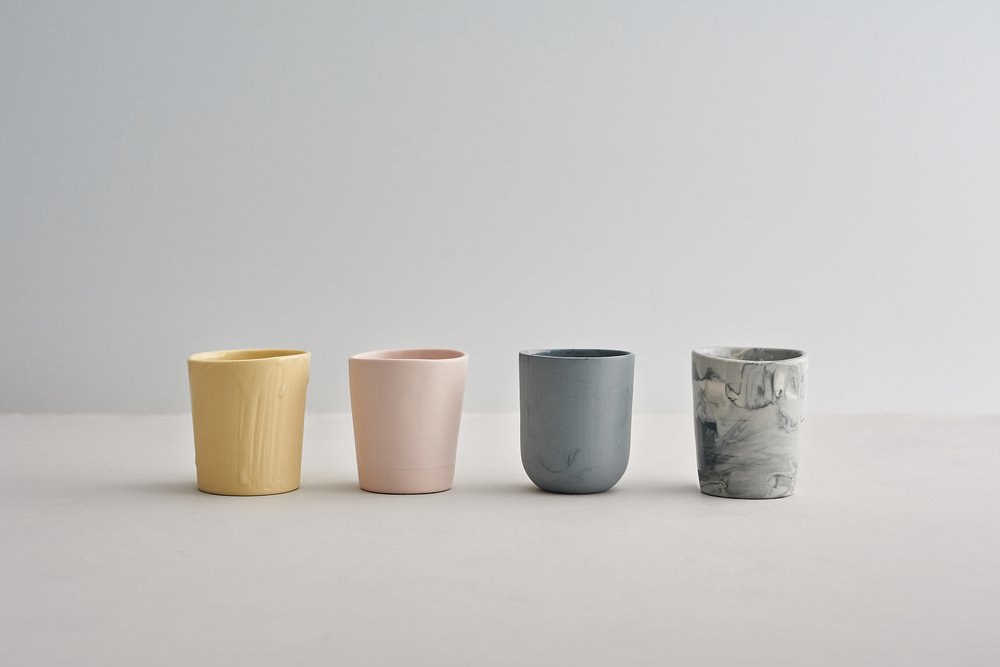  Subtly coloured handmade beakers photographed in line-up upon surface 