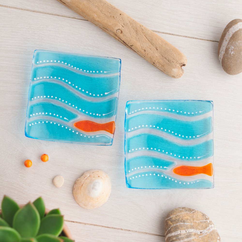  Two small glass dishes blue with orange fish design, on white background 