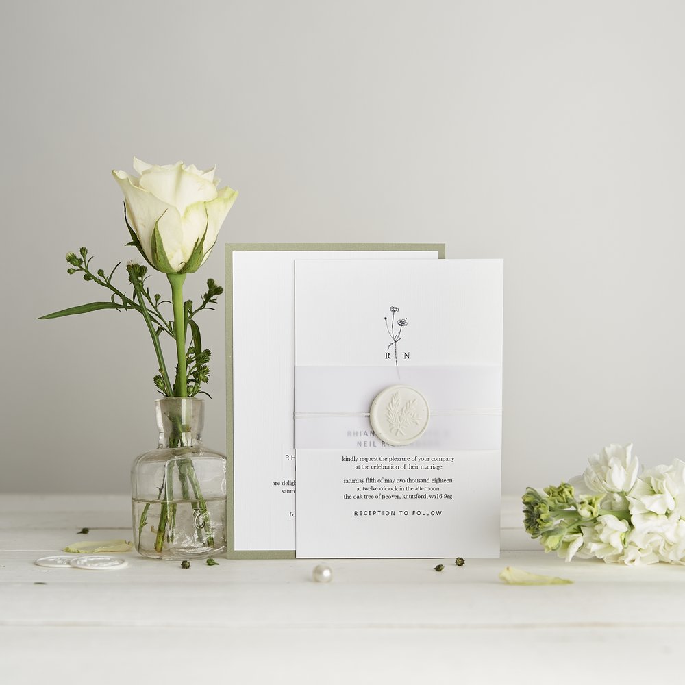  Wedding stationery invitations and detail card photographed next to fresh flower in small glass vase 