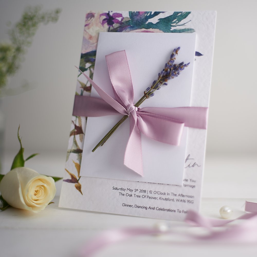 Wedding stationery photographed next to fresh flower in small glass vase out of focus in background 2 