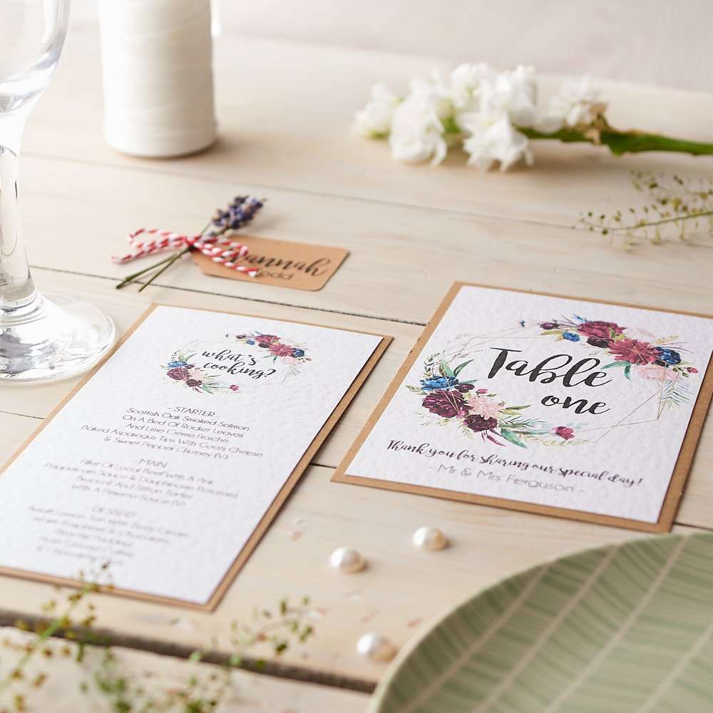  Mock-up of wedding stationery diagonally strewn across table with fresh flowers and champagne flute as props 2 