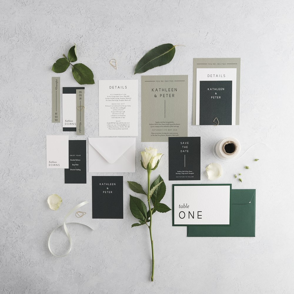  Flat-lat of complete wedding stationery suite layered with surrounding props including leaves and fresh flowers photographed upon concrete background 3 