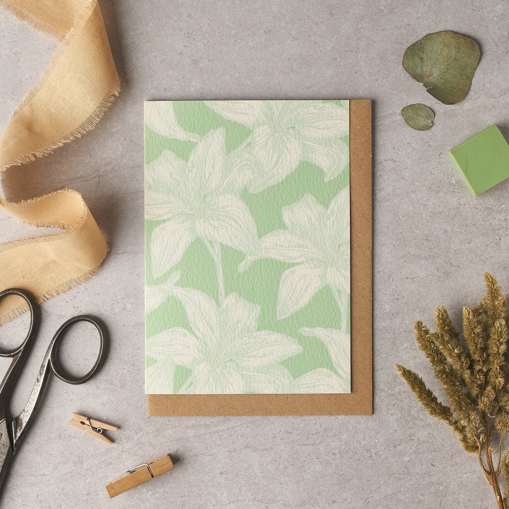  Nature themed illustrated greeting card shot against concrete background with props surrounding this 