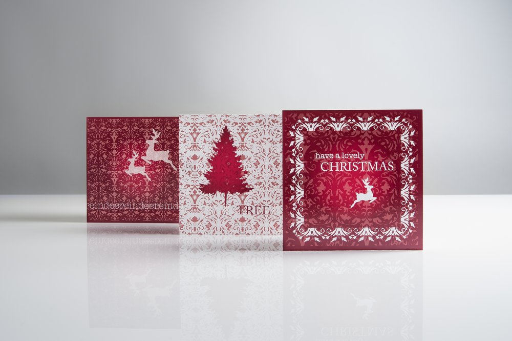  Christmas illustrated greeting cards photographed on white surface with focus upon shadows 