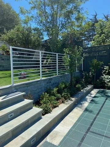 In the garden of a house there is a white iron gate made by the best iron expert in the area. 