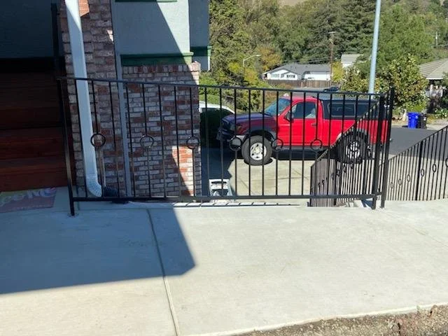 The house has a iron black gate separation, and behind it there is a red truck. 