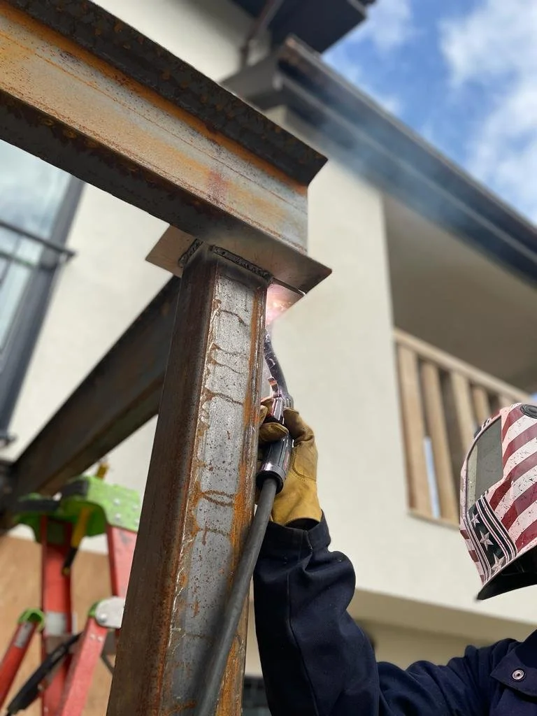 The expertise in action as our professional welds a column in a house. Dressed in a protective uniform, mask, and gloves, our skilled artisan ensures precision and safety in every detail.