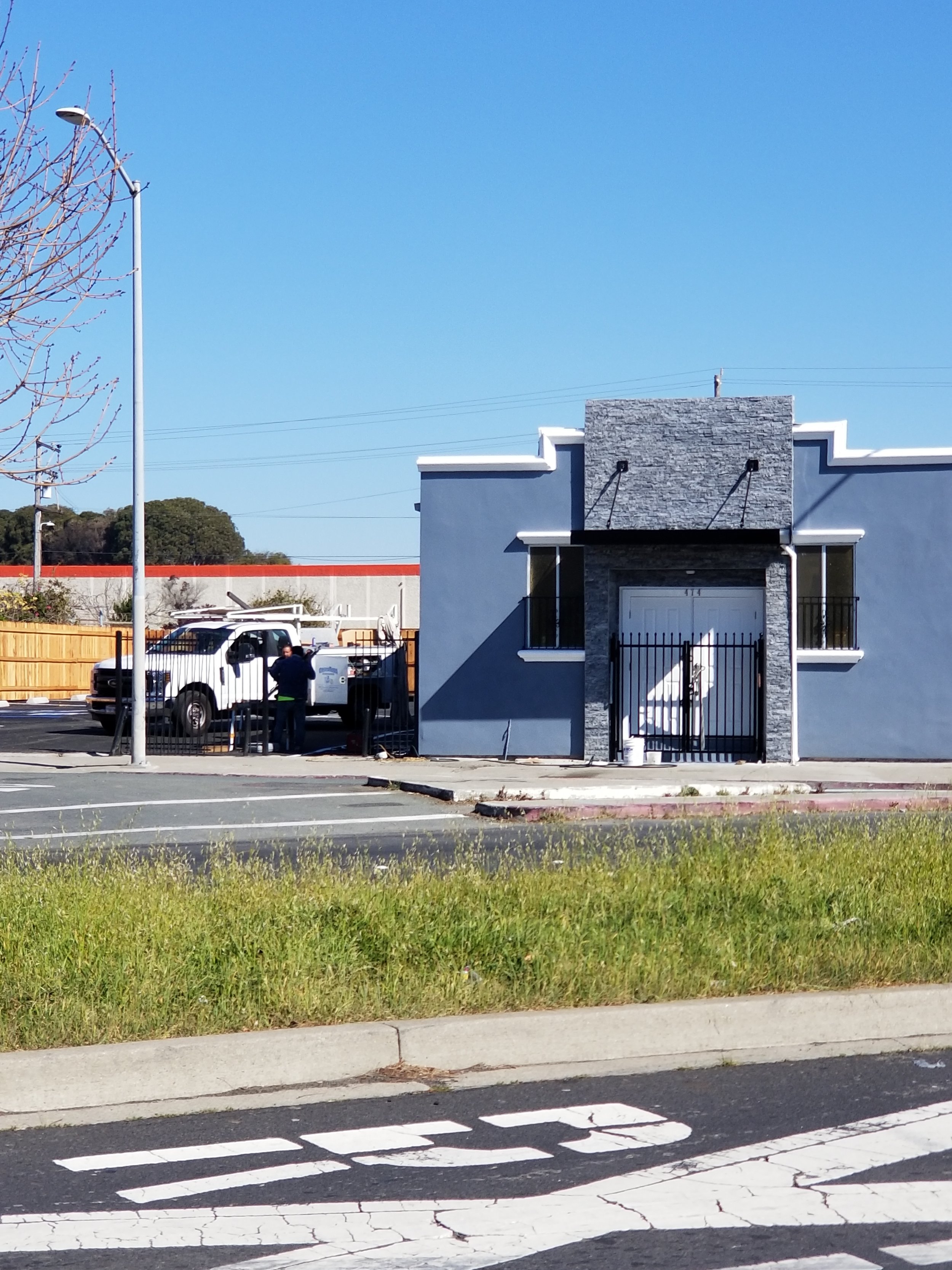 The iron awnings shadow projects against the backdrop of a  grey house, accentuating the white door.
