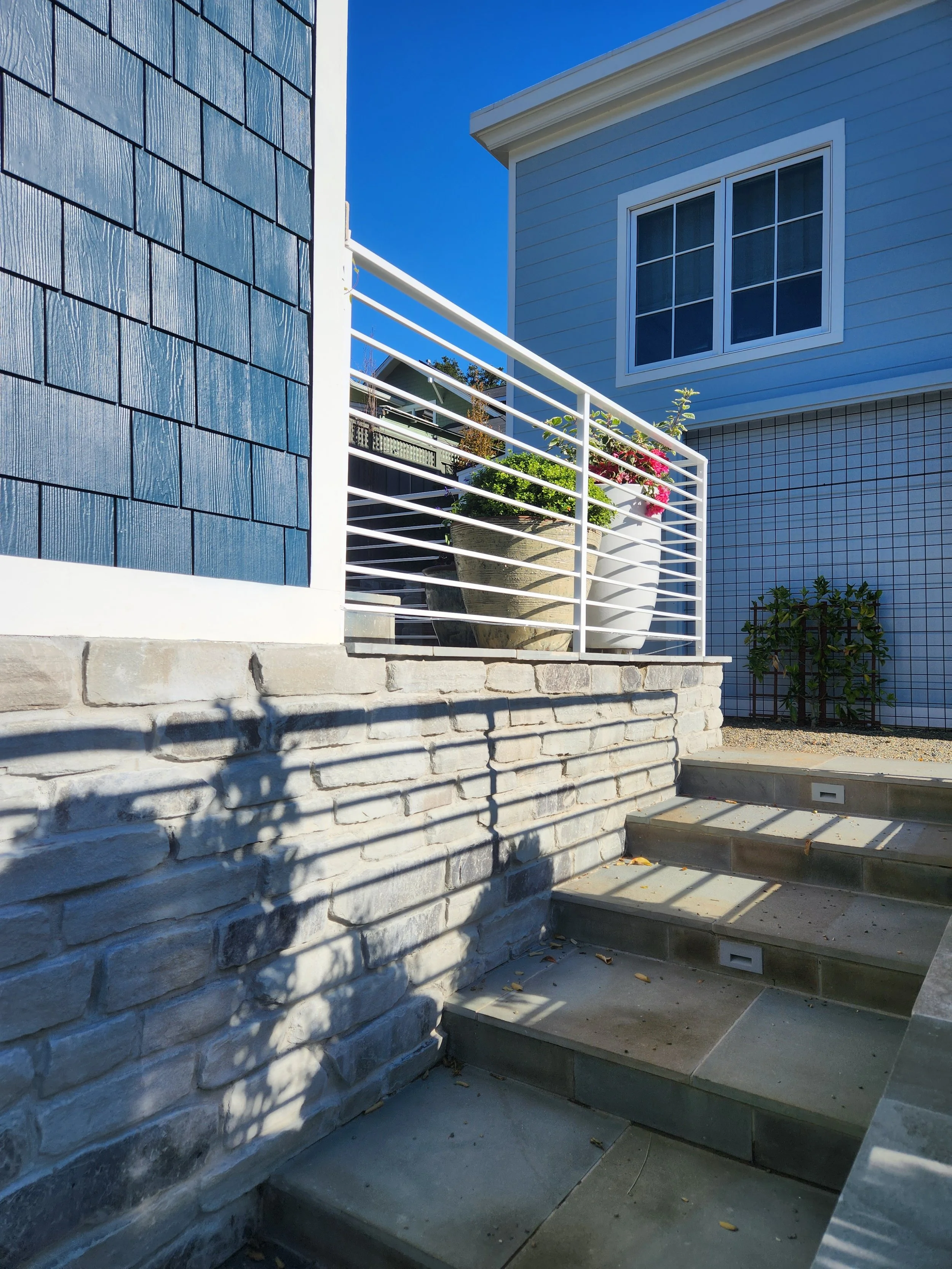 Small white rectangular fence next to the stairs and the blue two-story house