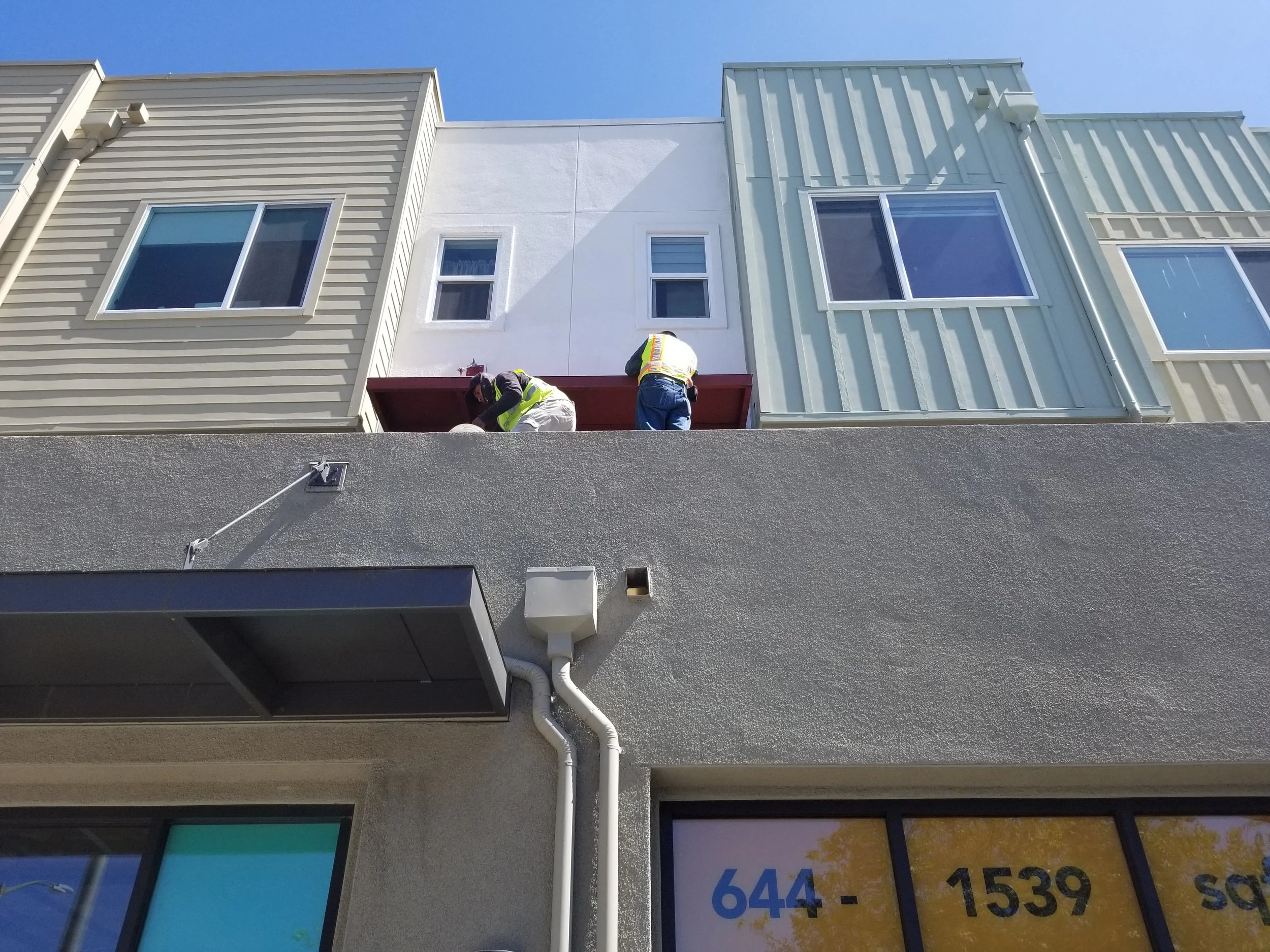 Two members of the iron and welding team are working on the top office roof. They are dressed with their protective uniform.