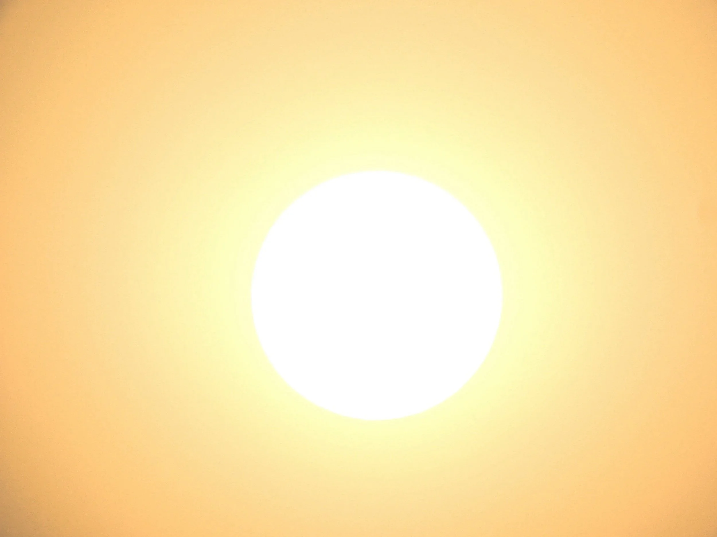 A bright white circular light or glow on a yellow background.