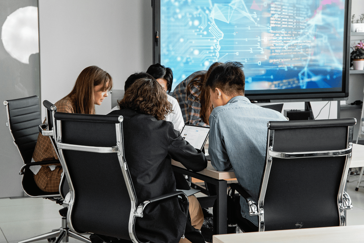Group meeting with digital analytics display in background.