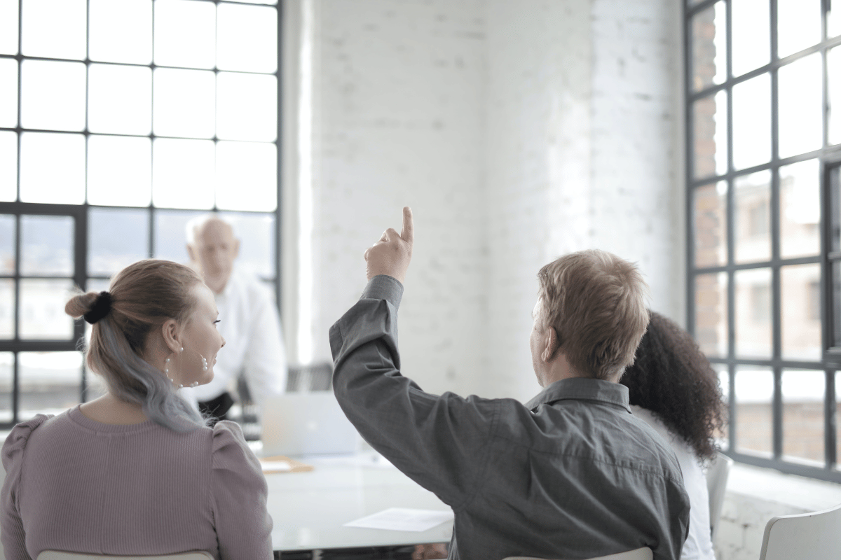 Business meeting in action with participants raising hands to give feedback.