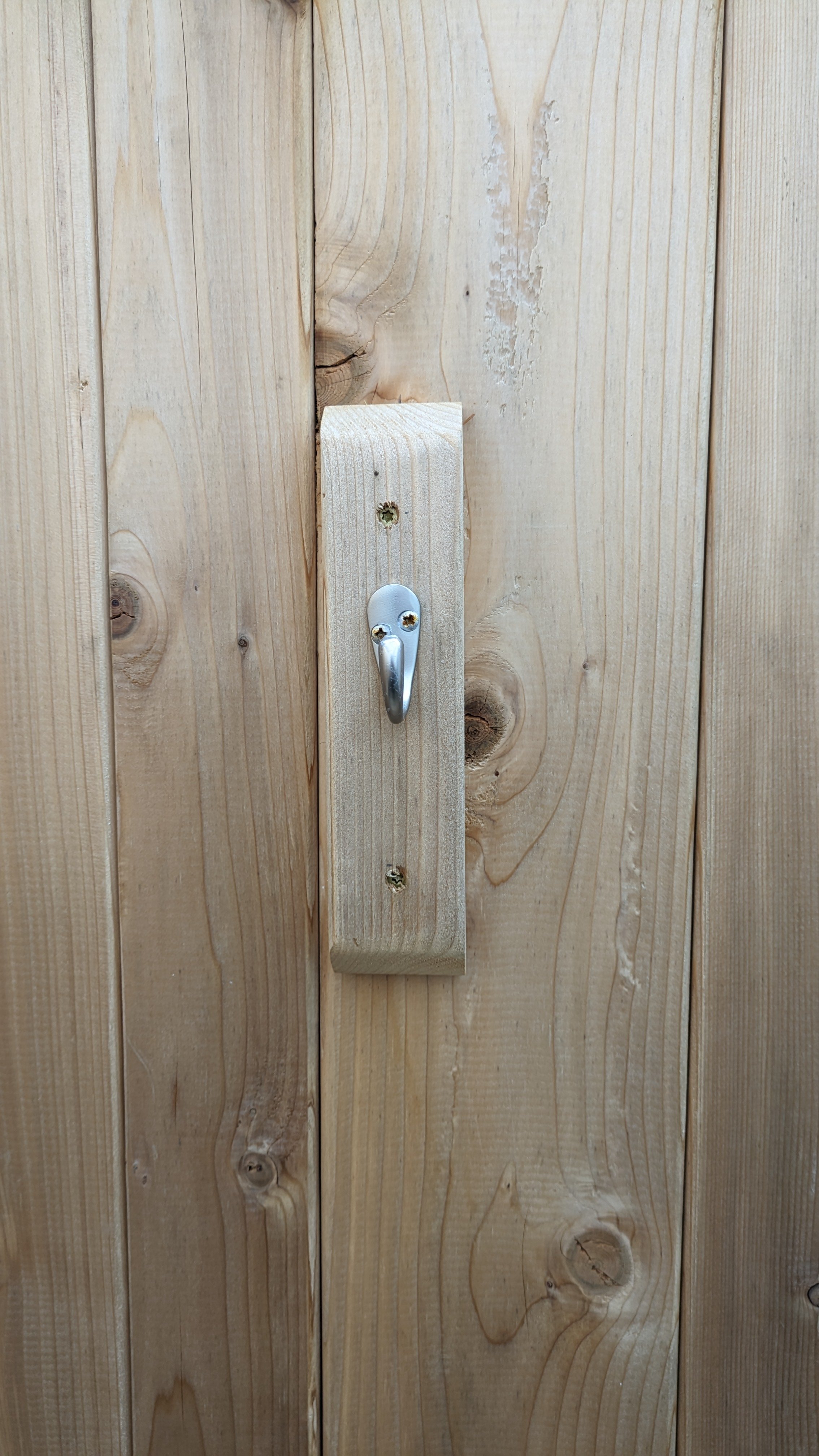 Close-up of a wooden wall with a metal hook attached to a vertical wooden plank.