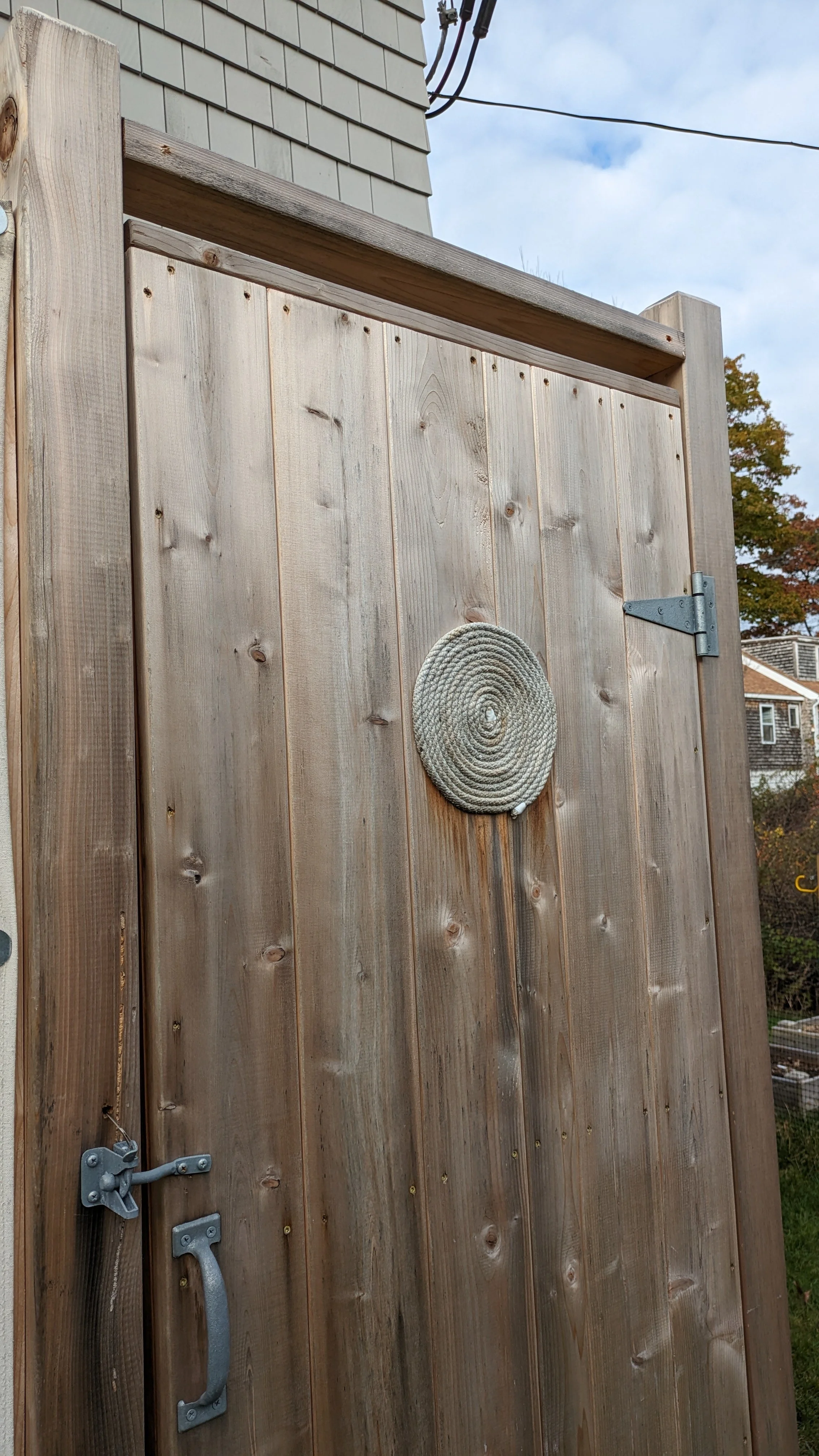 Wooden outdoor shower with a rope coil on the door