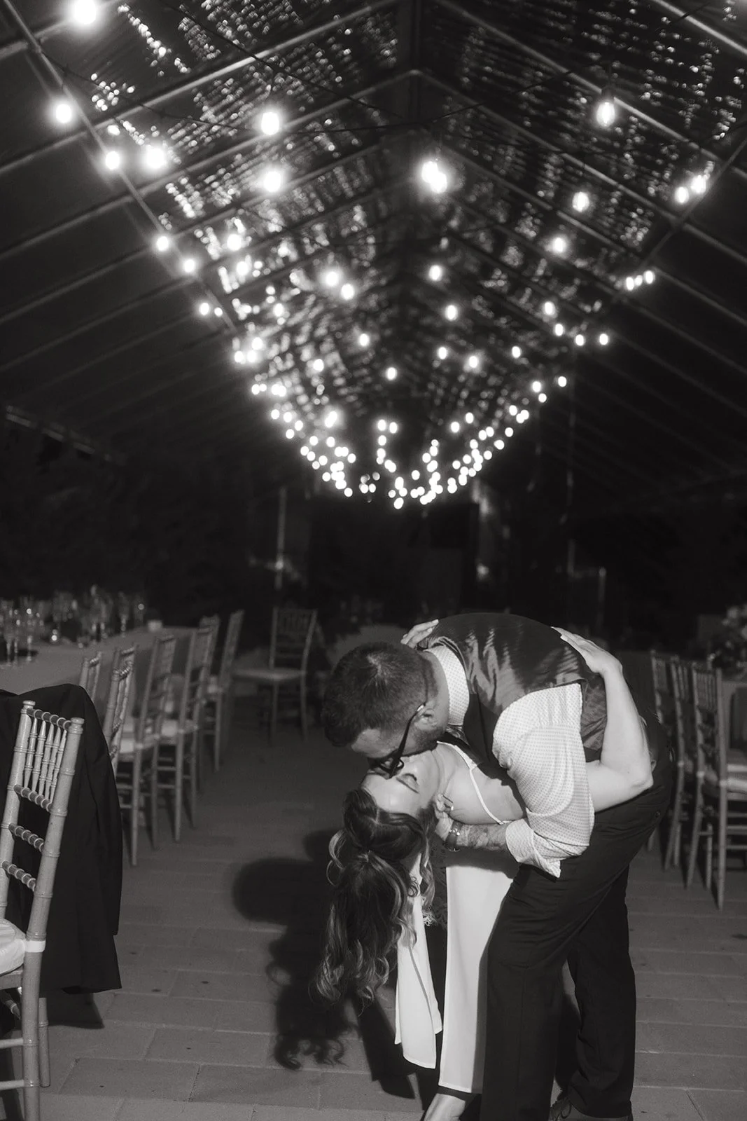wedding couple at after party kissing under wedding lights at herb lyceum