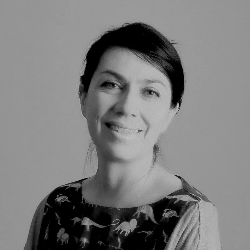 Retrato en blanco y negro de una mujer sonriendo con el cabello recogido, usando una blusa con estampado de animales.