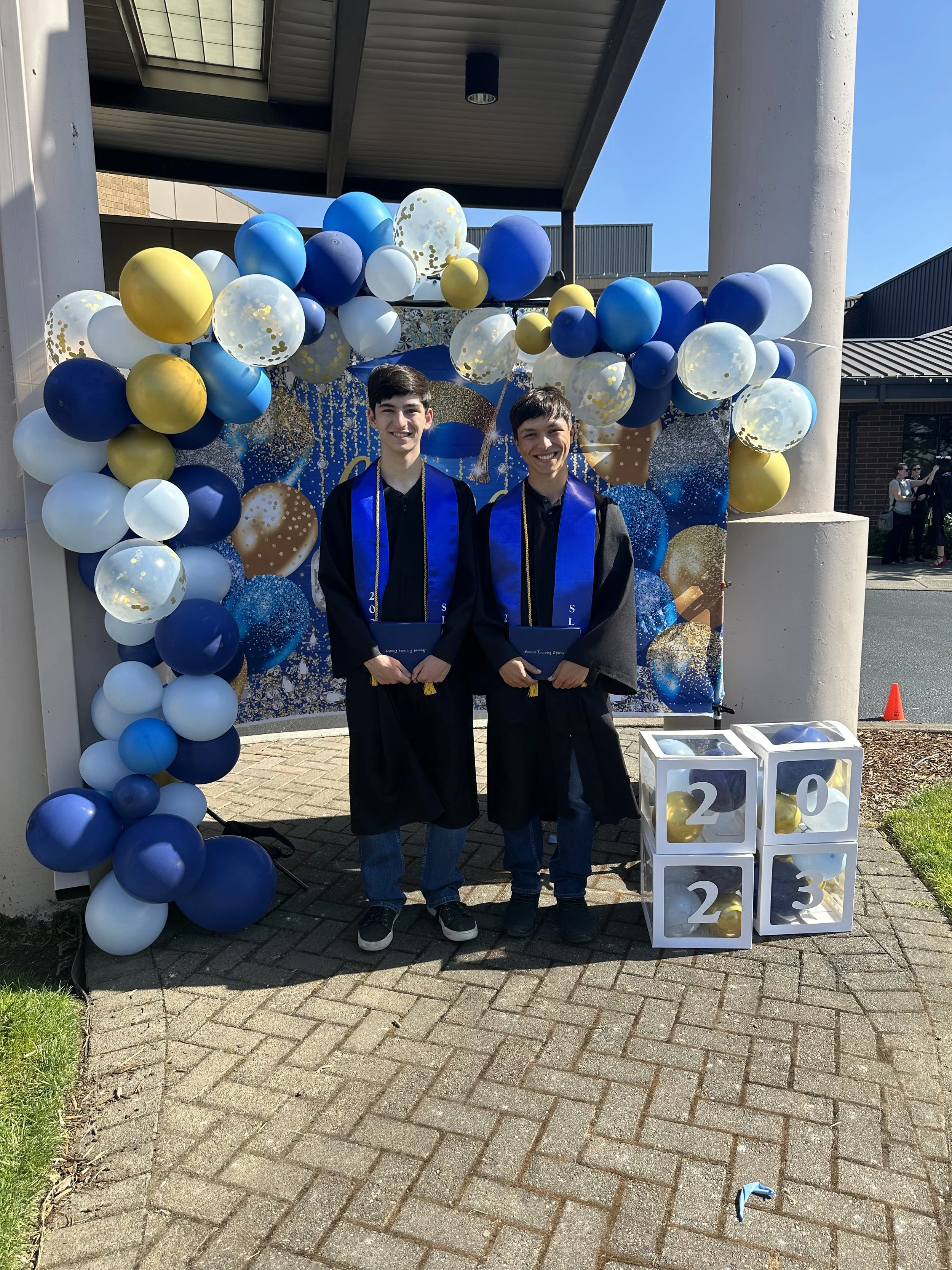 Two graduates posing with blue regalia