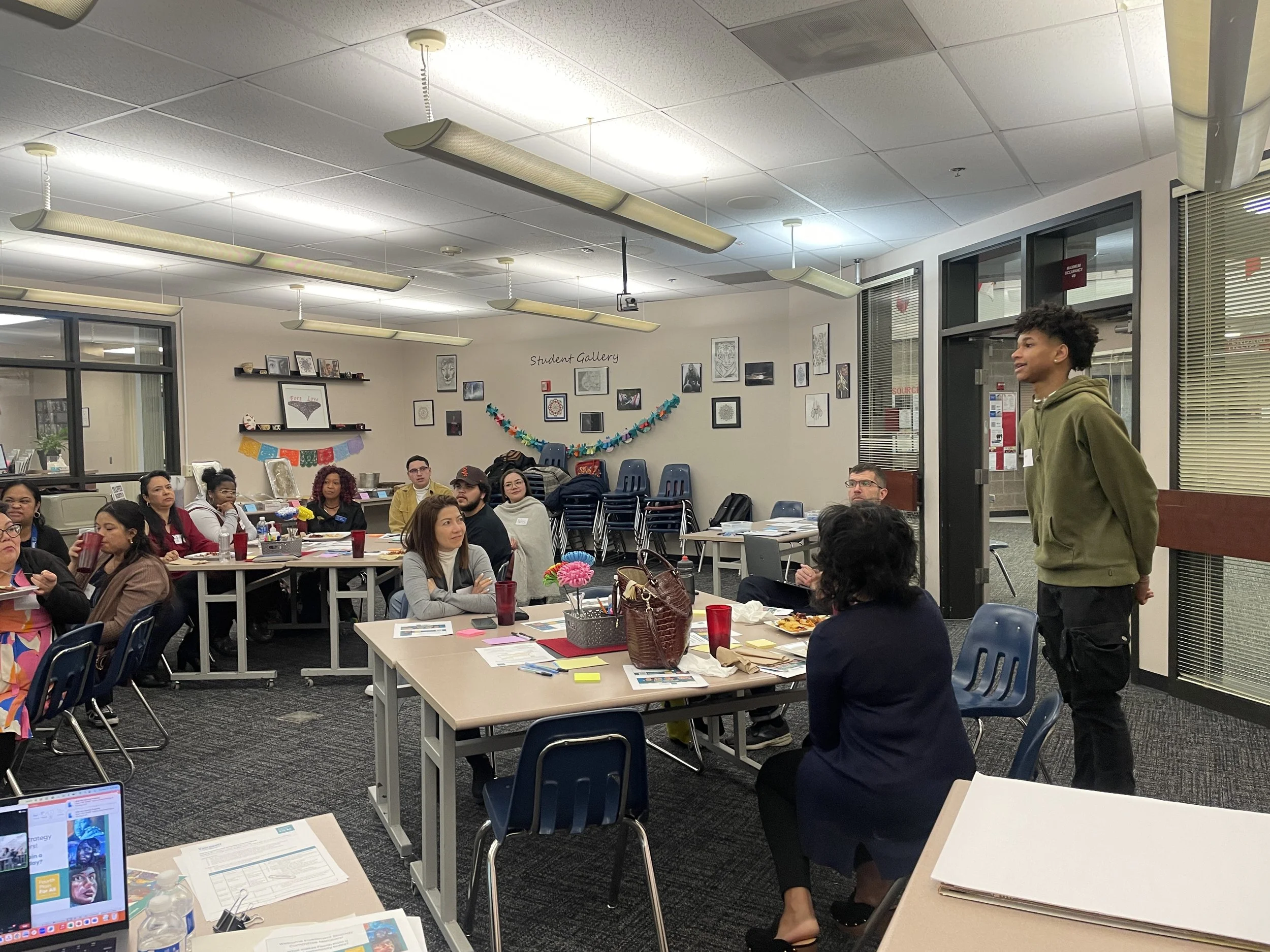 An image of a classroom filled with people sitting at different tables