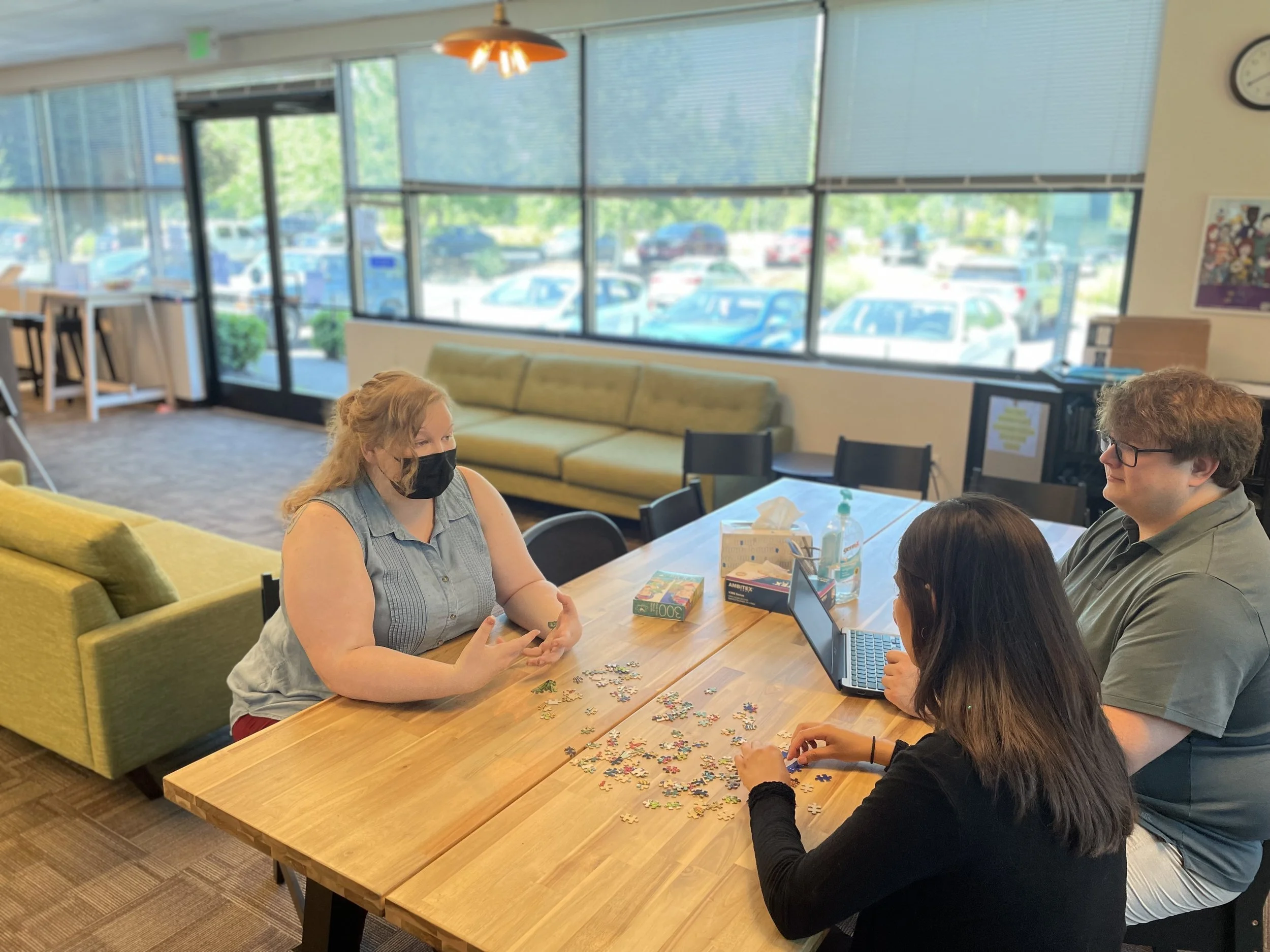 An image of three individuals talking and working on a puzzle