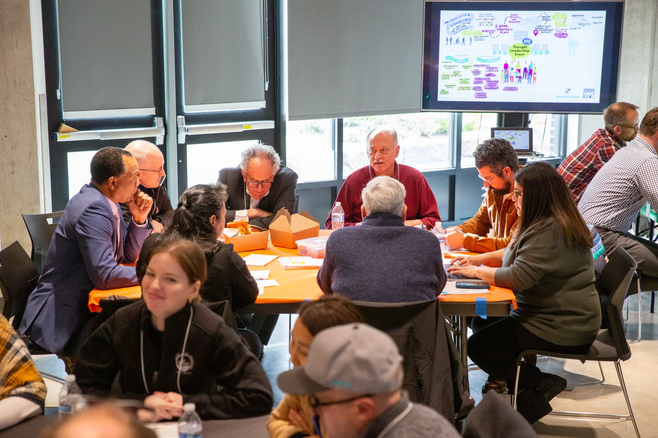 A group of people sitting around a table at a workshop, talking together.
