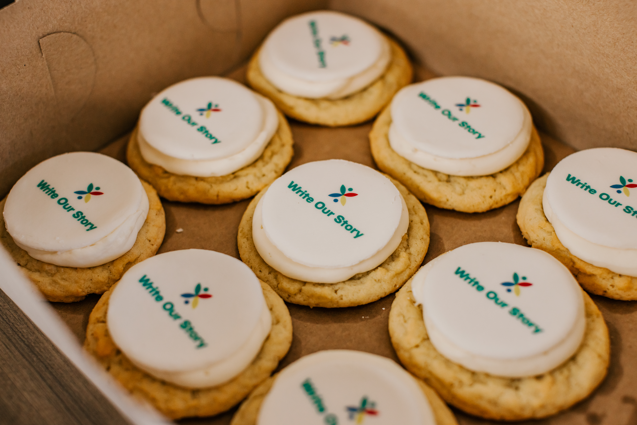 A box of cookies that have the Write Our Story logo on them
