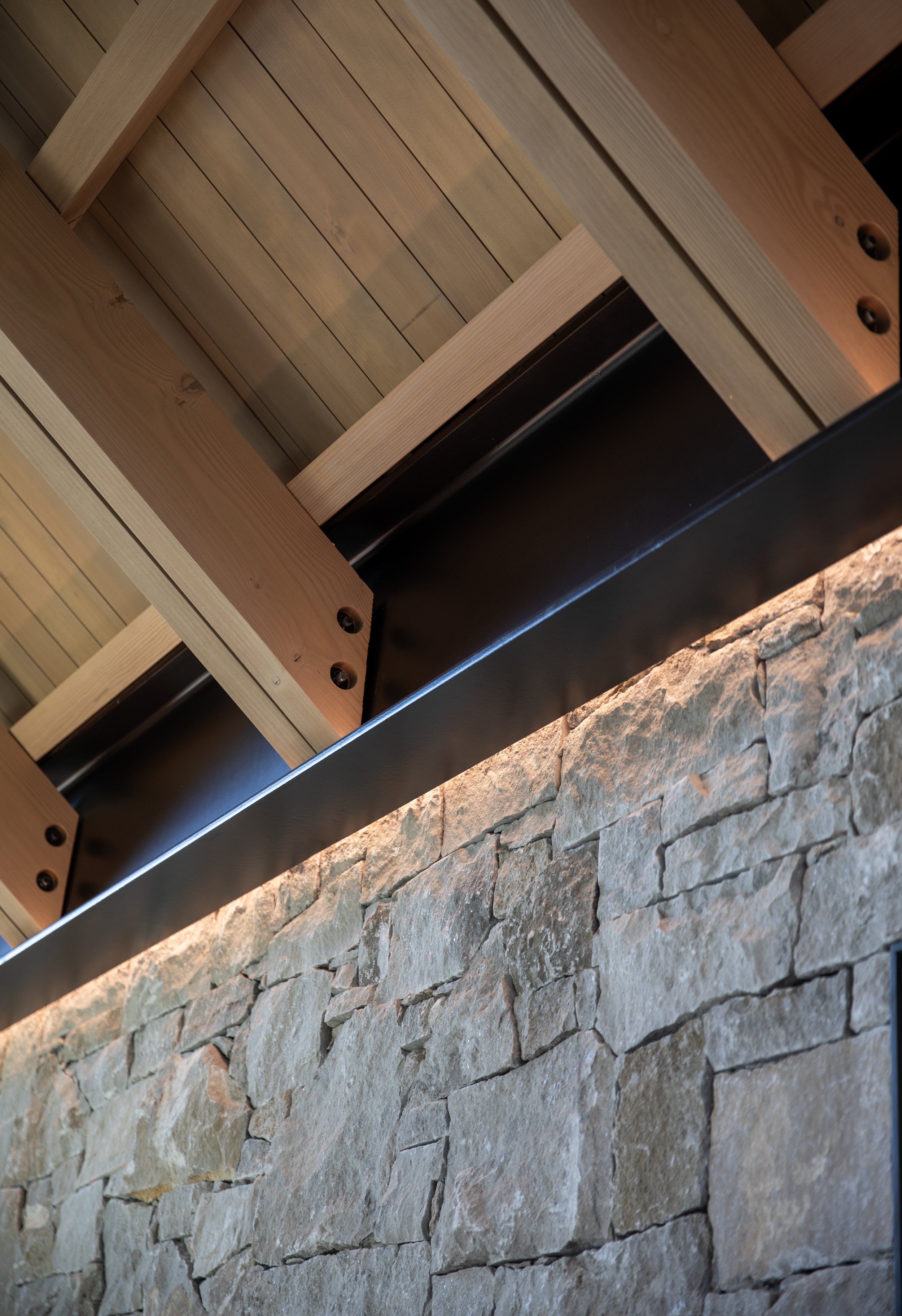 Close-up of a wooden and stone fireplace mantel with metal accents.
