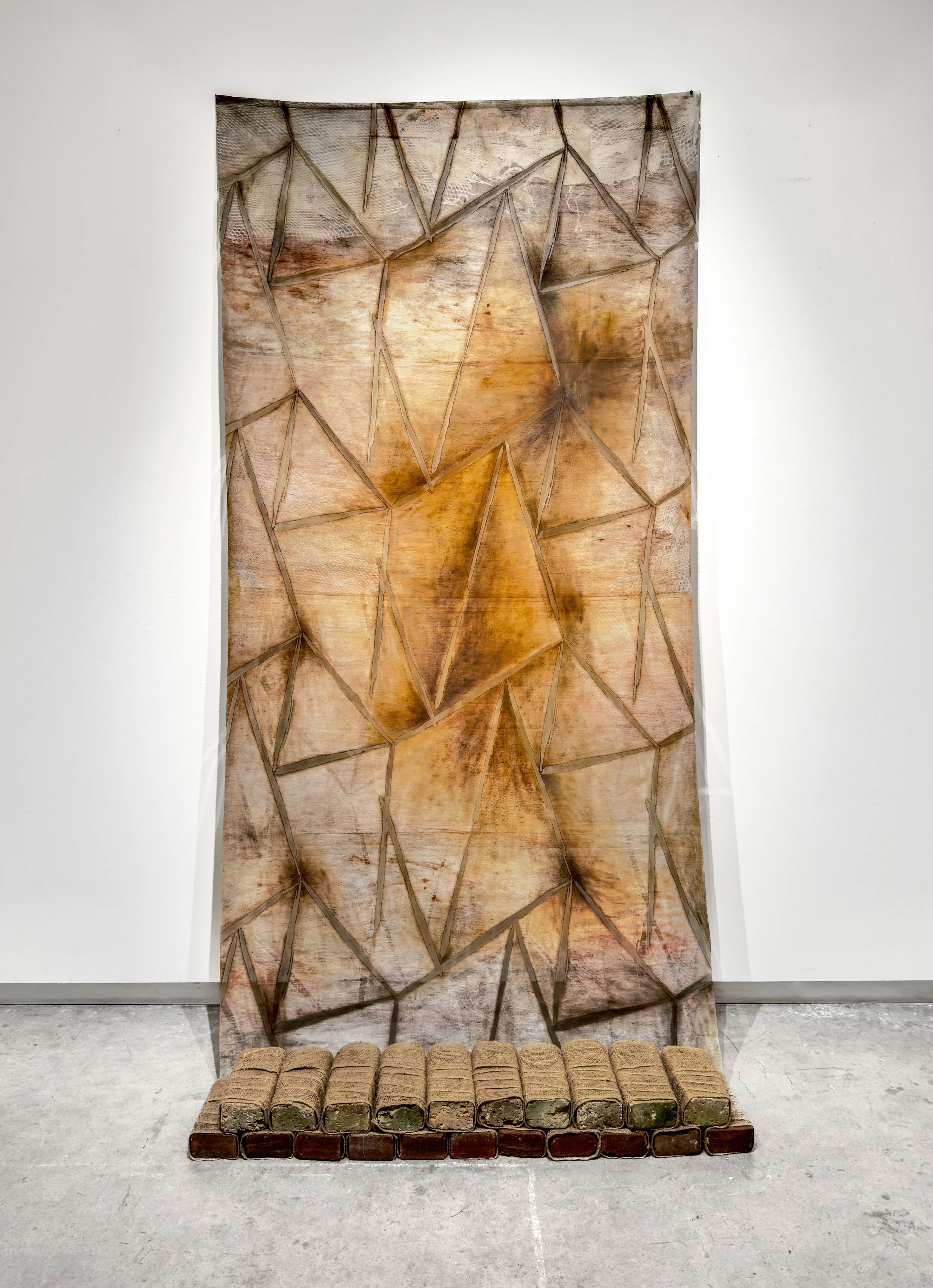 "Desire Paths Land at Crossroads",  2025, Monotyped Relief Ink and Oil on Fabric, Found Bricks, Burlap (40” x 86”) - Collaboration with Evan McHenry