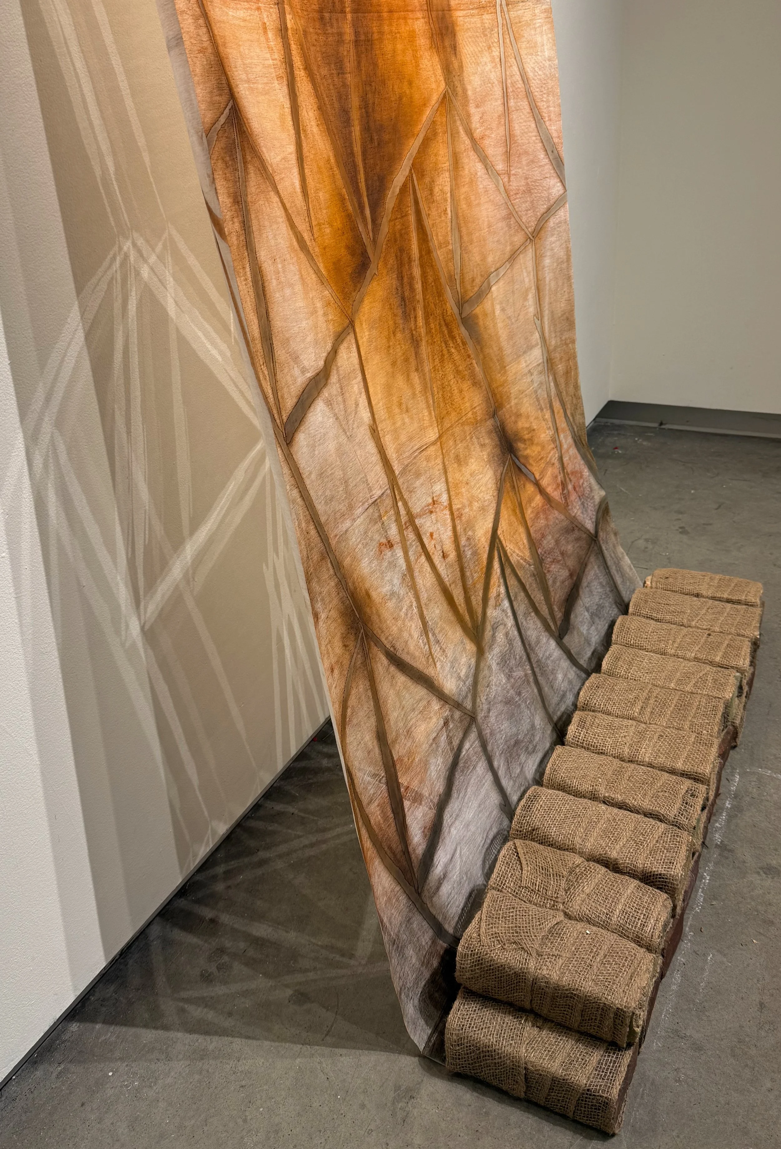 "Desire Paths Land at Crossroads",  2025, Monotyped Relief Ink and Oil on Fabric, Found Bricks, Burlap (40” x 86”) - Collaboration with Evan McHenry