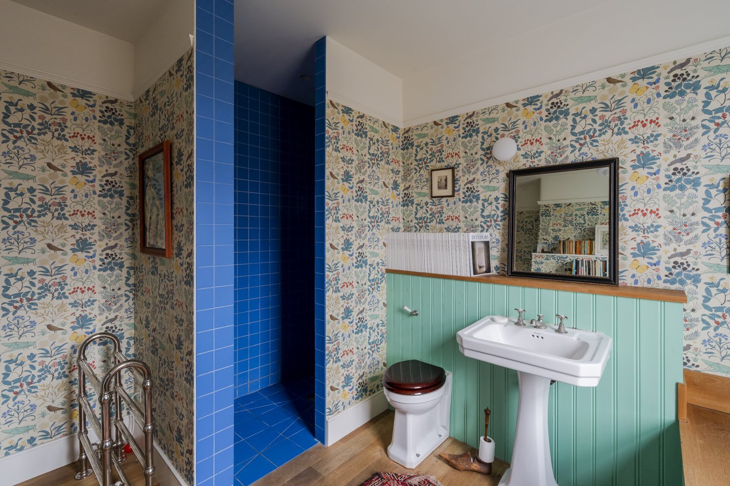 The blue tiles and green woodwork pick from the beautiful wallpaper for an eclectic but still cohesive feel.