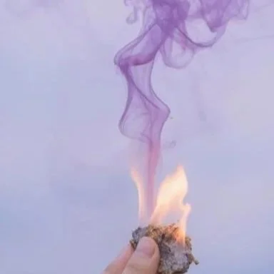 small+fire+with+minimal+smoke+in+shades+of+lavenders+and+purples+with+pieces+of+a+white+letter+burning+in+it+and+light+blue+sky.jpg