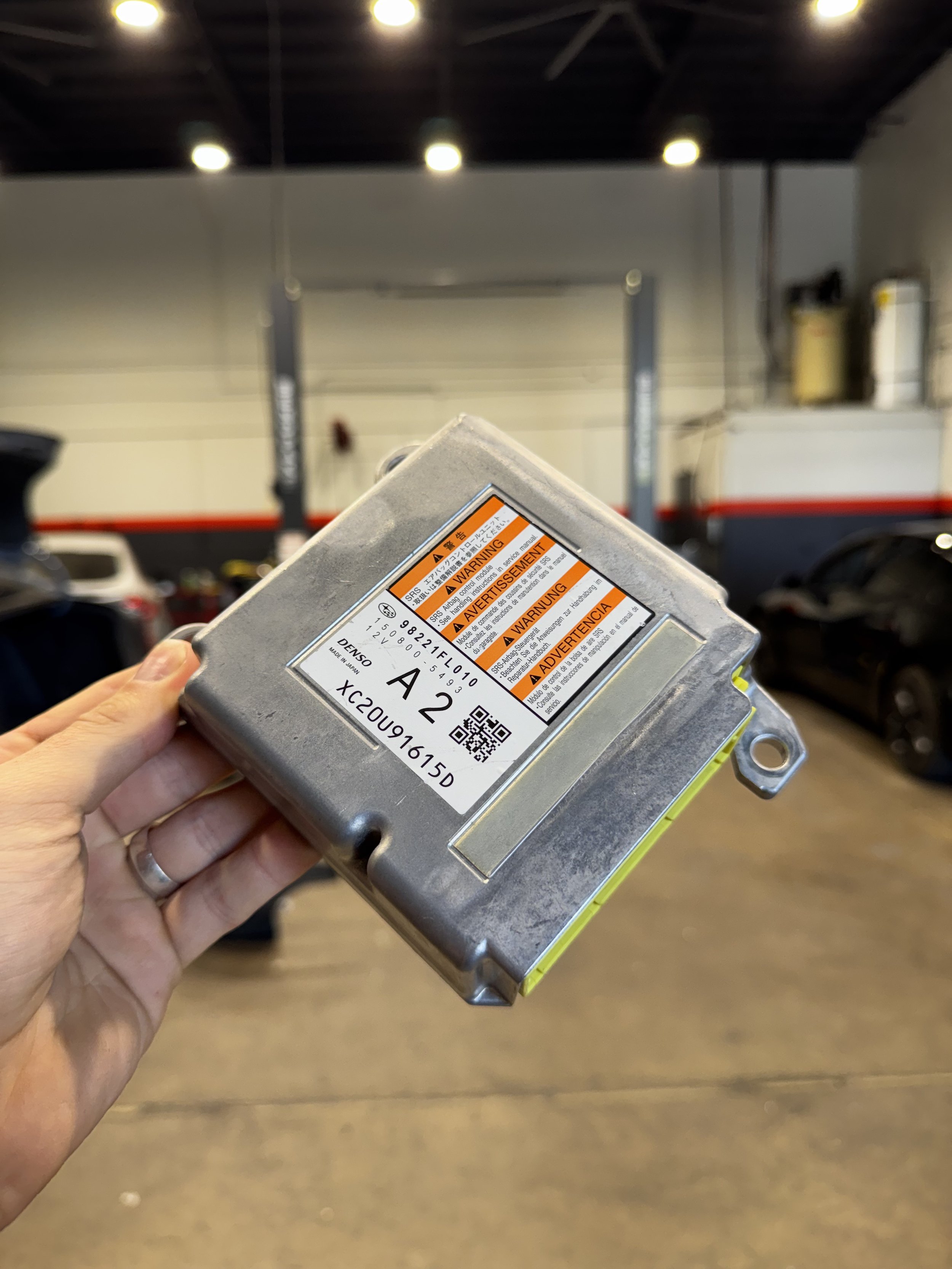 A metal automotive control module with multiple electrical connectors and a label indicating it is a Restraint Control Module.