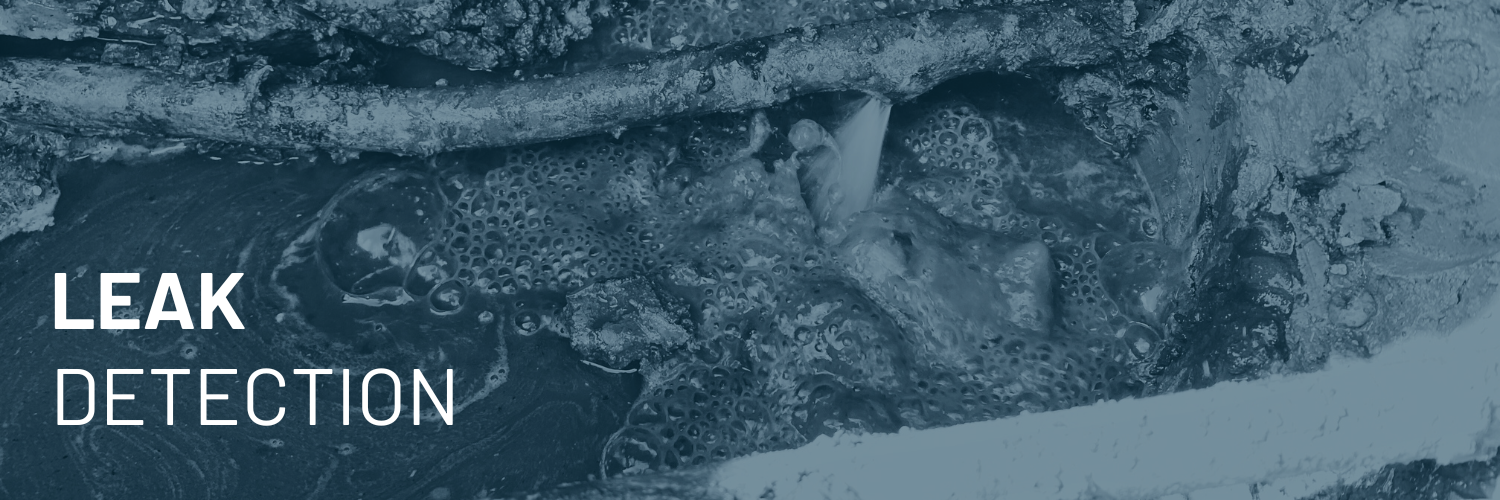 Close-up of water leaking from a pipe with bubbles and foam visible surrounding the leak.