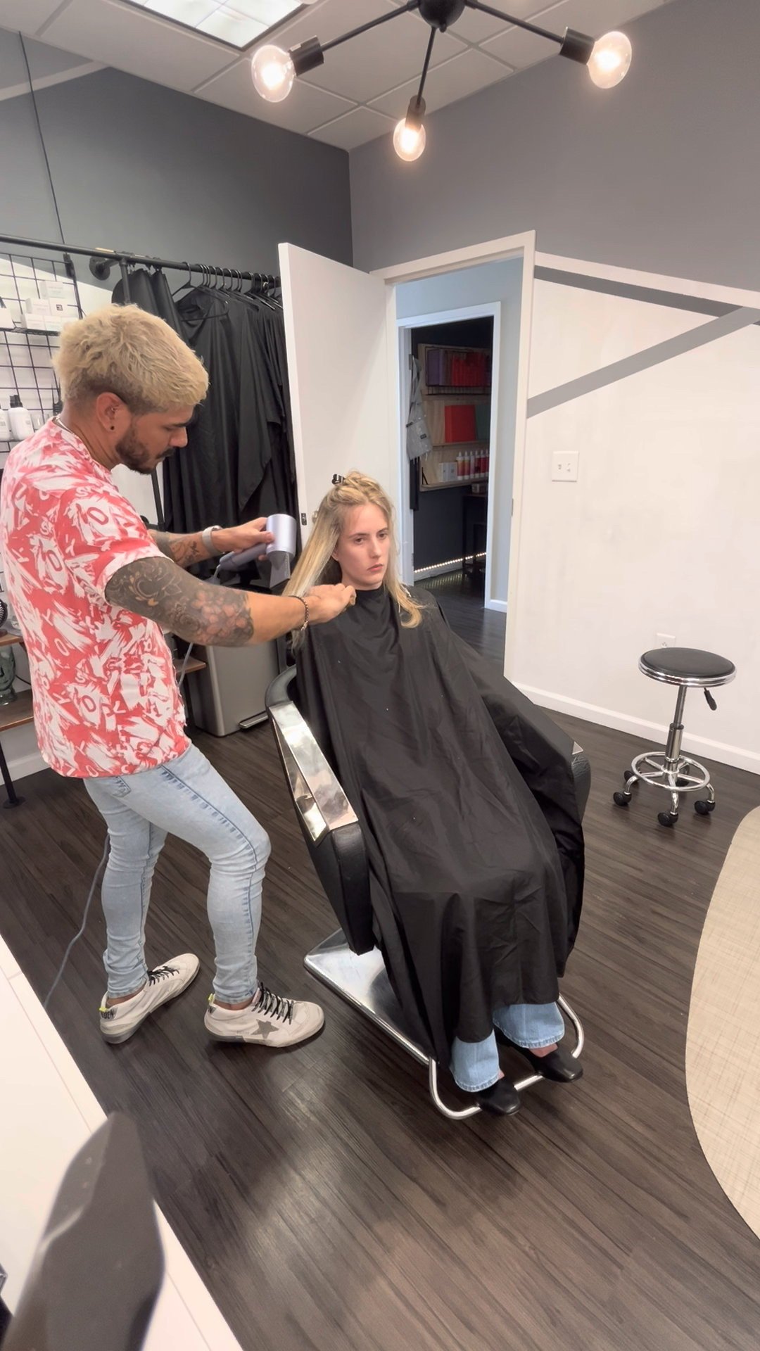 Hair stylist blow-drying client's hair in salon
