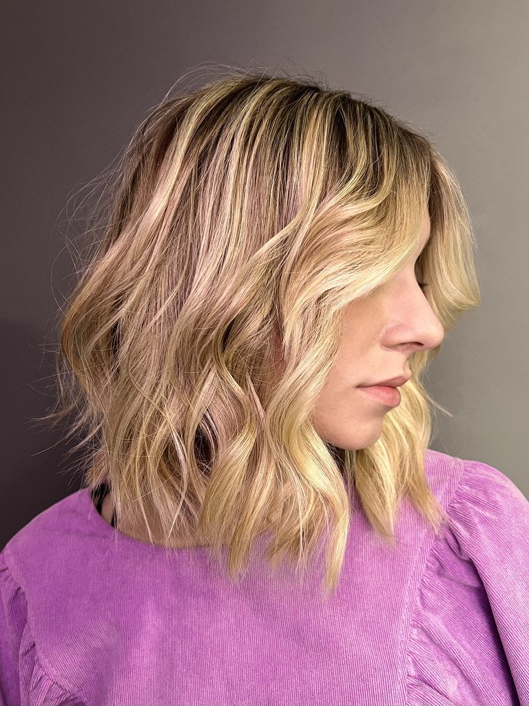 Woman with wavy blonde bob hairstyle wearing a purple shirt