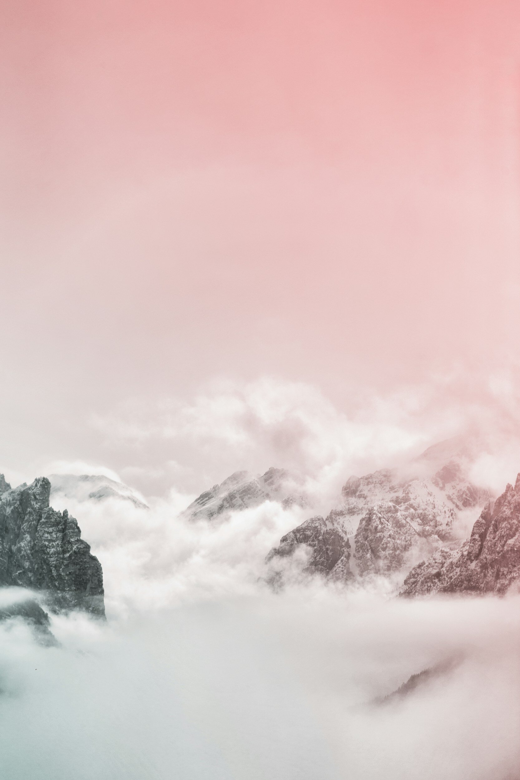 Snow-covered mountains with mist and a pink sky.