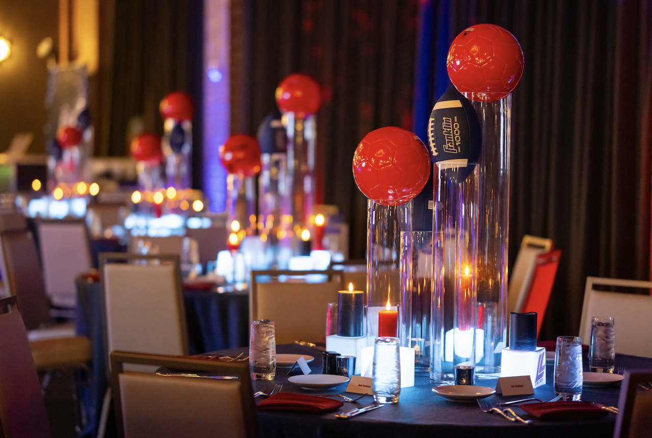 red soccer balls and blue footballs on glass cylinders