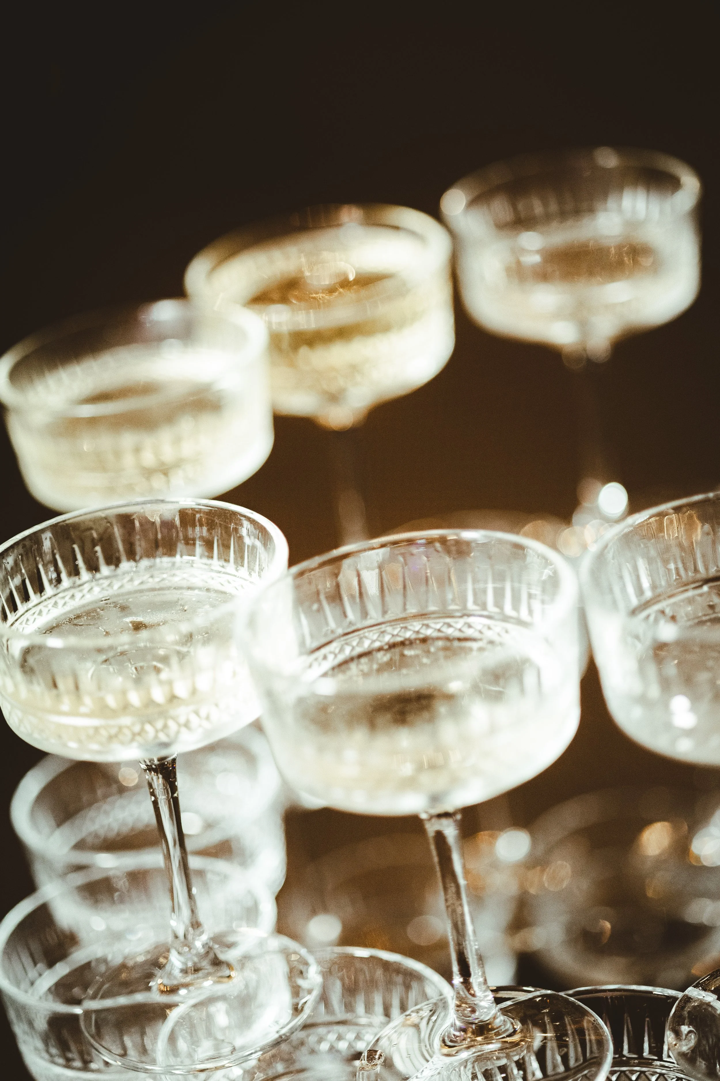 Multiple empty champagne glasses stacked together on a dark surface.