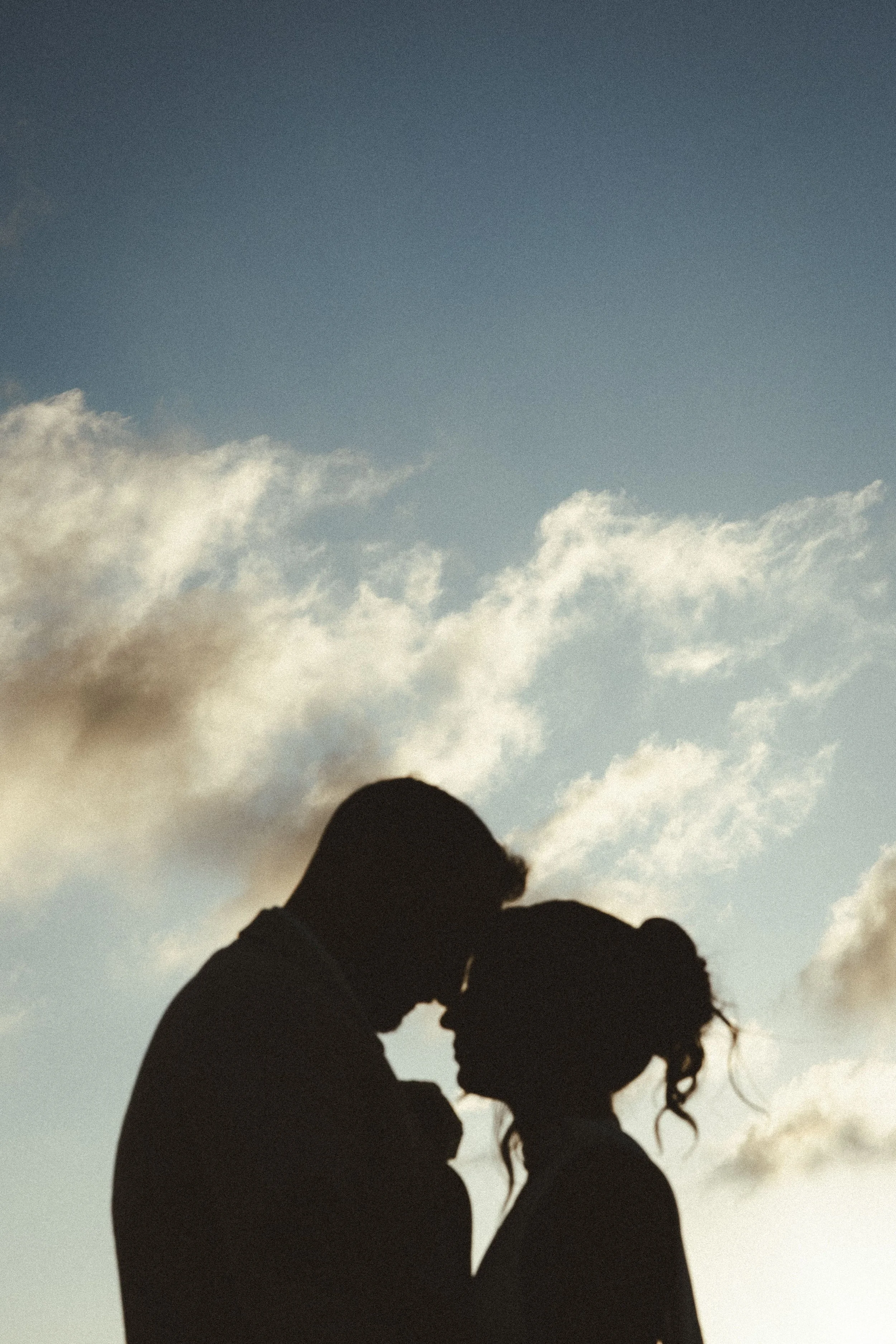 Silhouette of a couple outdoors against a cloudy sky, during their wedding photoshoot in cancun.