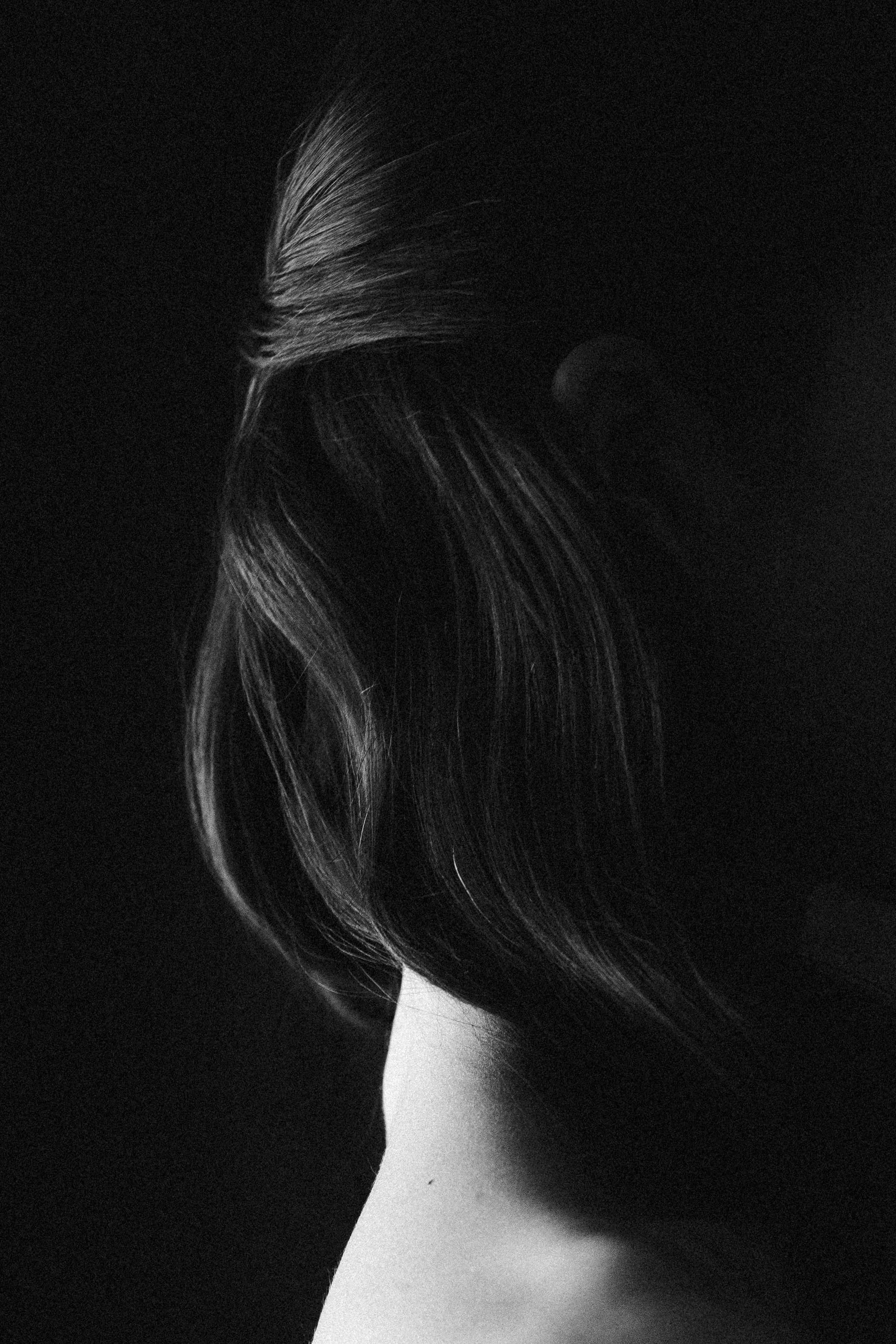 Black and white close-up of a bride's hairstyle, showing a section of long, flowing hair and a sharp contrast in lighting.