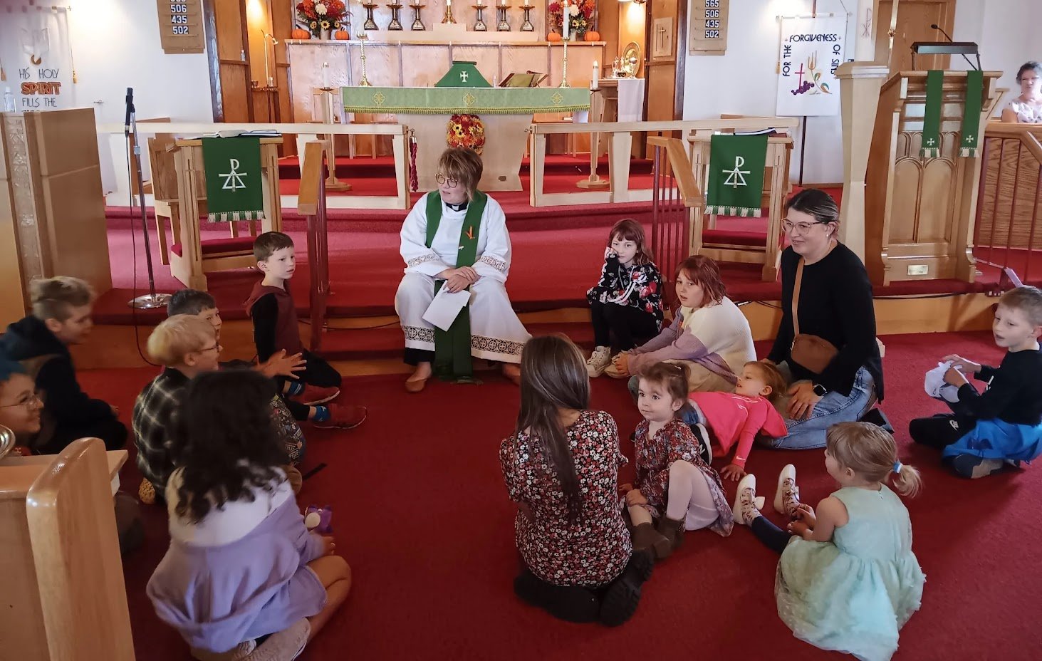 Children sitting with a teacher in a church setting, engaged in a lesson.
