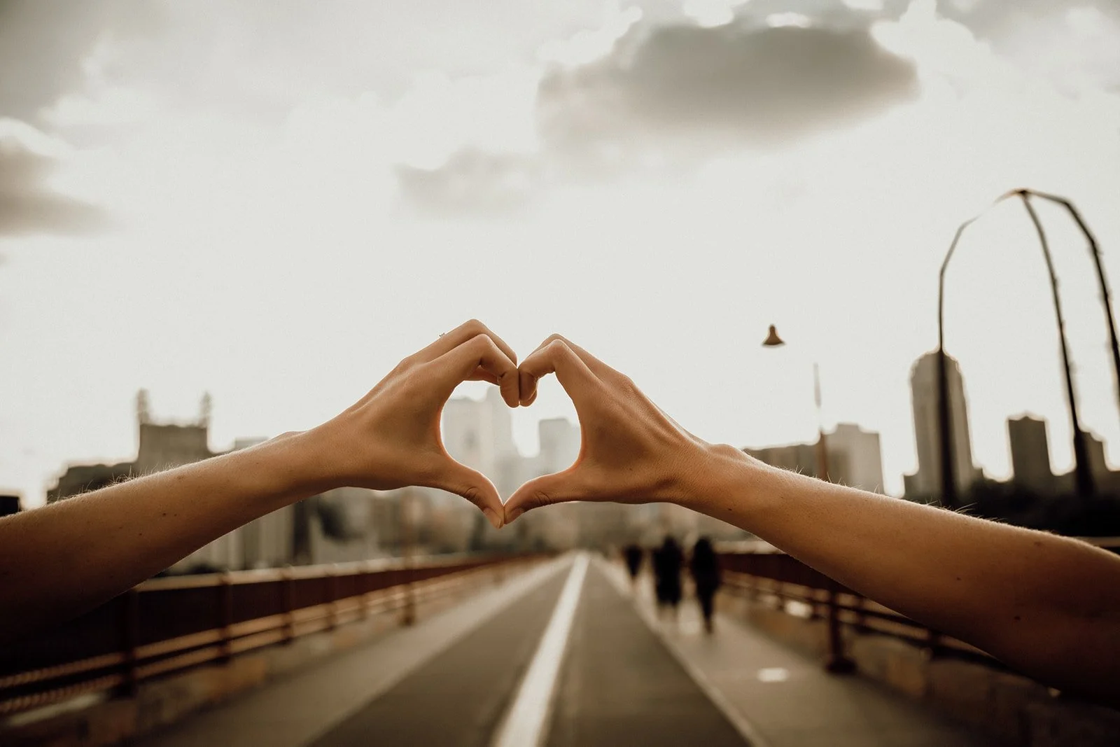 Hands creating a heart shape over a city skyline, representing the intentional structure and relational safety of the Inner Circle container.