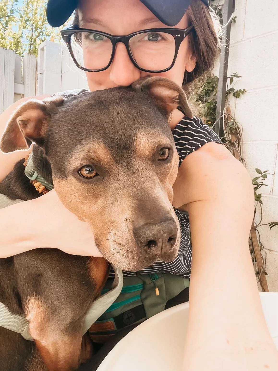 Dr. Elizabeth holding her dog Luna during a calm outdoor moment, representing embodied nervous system regulation and grounded presence.