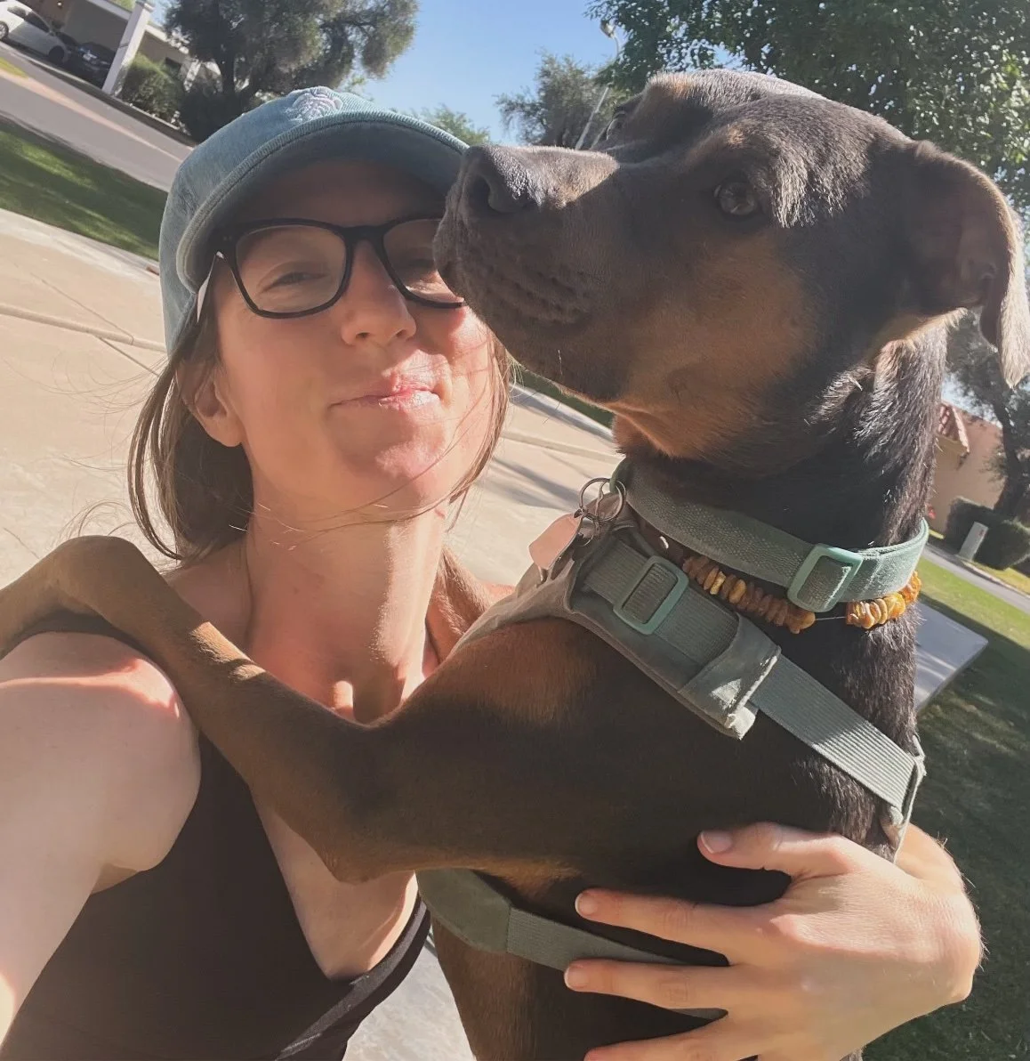 Woman holding her dog closely outdoors, representing calm connection, regulation, and consistent energetic awareness