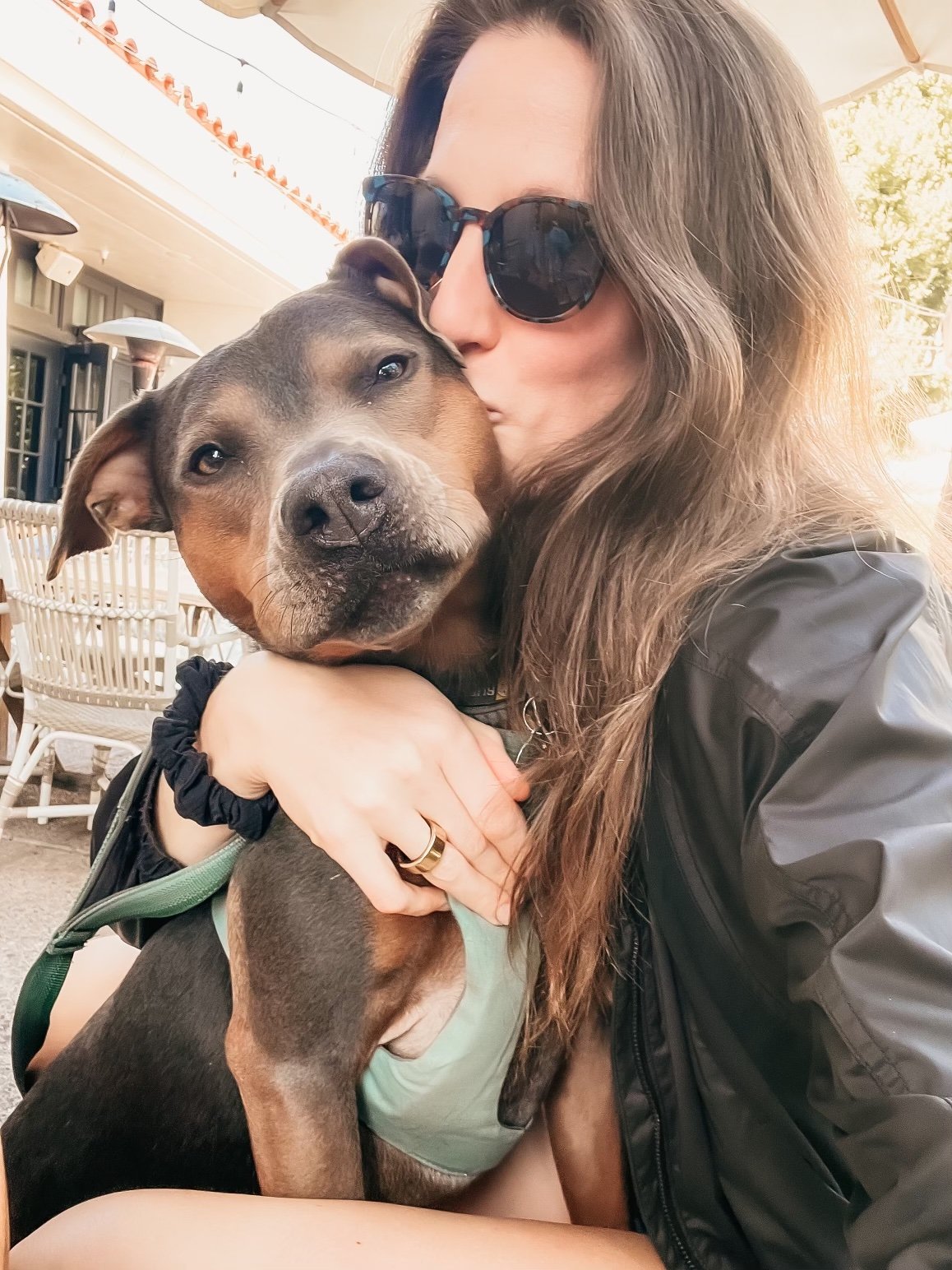 Dr. Elizabeth holding and kissing her dog Luna outdoors, illustrating calm nervous system regulation and embodied healing.