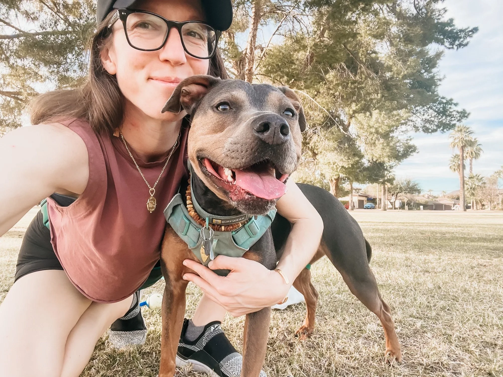 Dr. Elizabeth relaxing with her dog Luna on the grass, representing the ease and authenticity that emerge through nervous system healing.