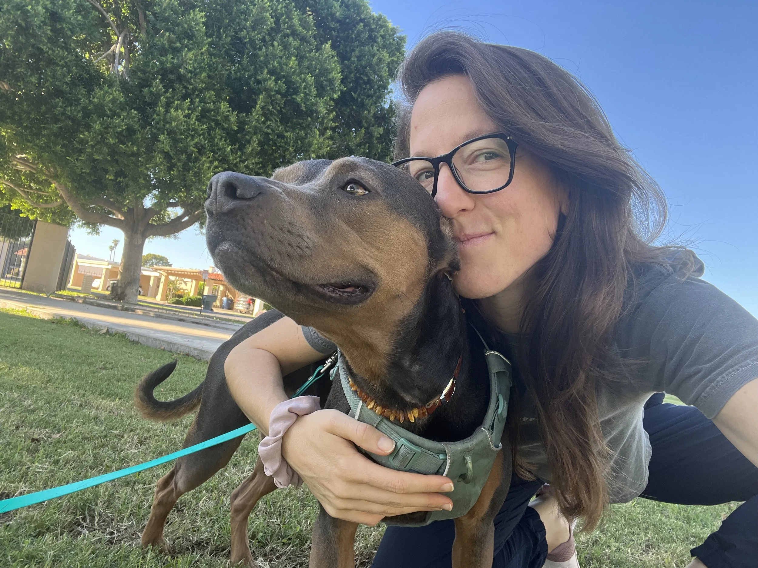 Dr. Elizabeth kneeling in a park holding Luna, symbolizing nervous system maturity and embodied growth.