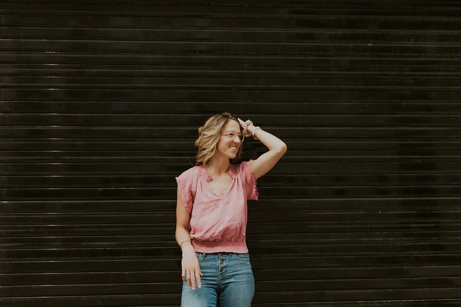 Dr. Elizabeth standing against a dark wall, representing intuitive healing, personal alignment, and embodied connection to holistic practices.