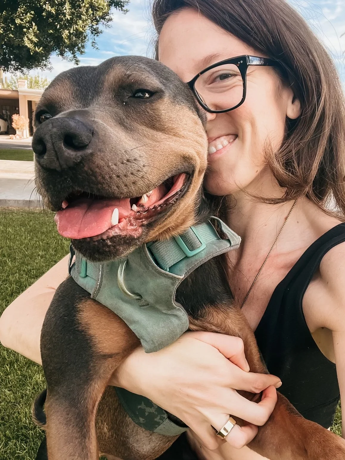 Woman holding her dog outdoors, representing grounded self-trust, connection, and embodied healing