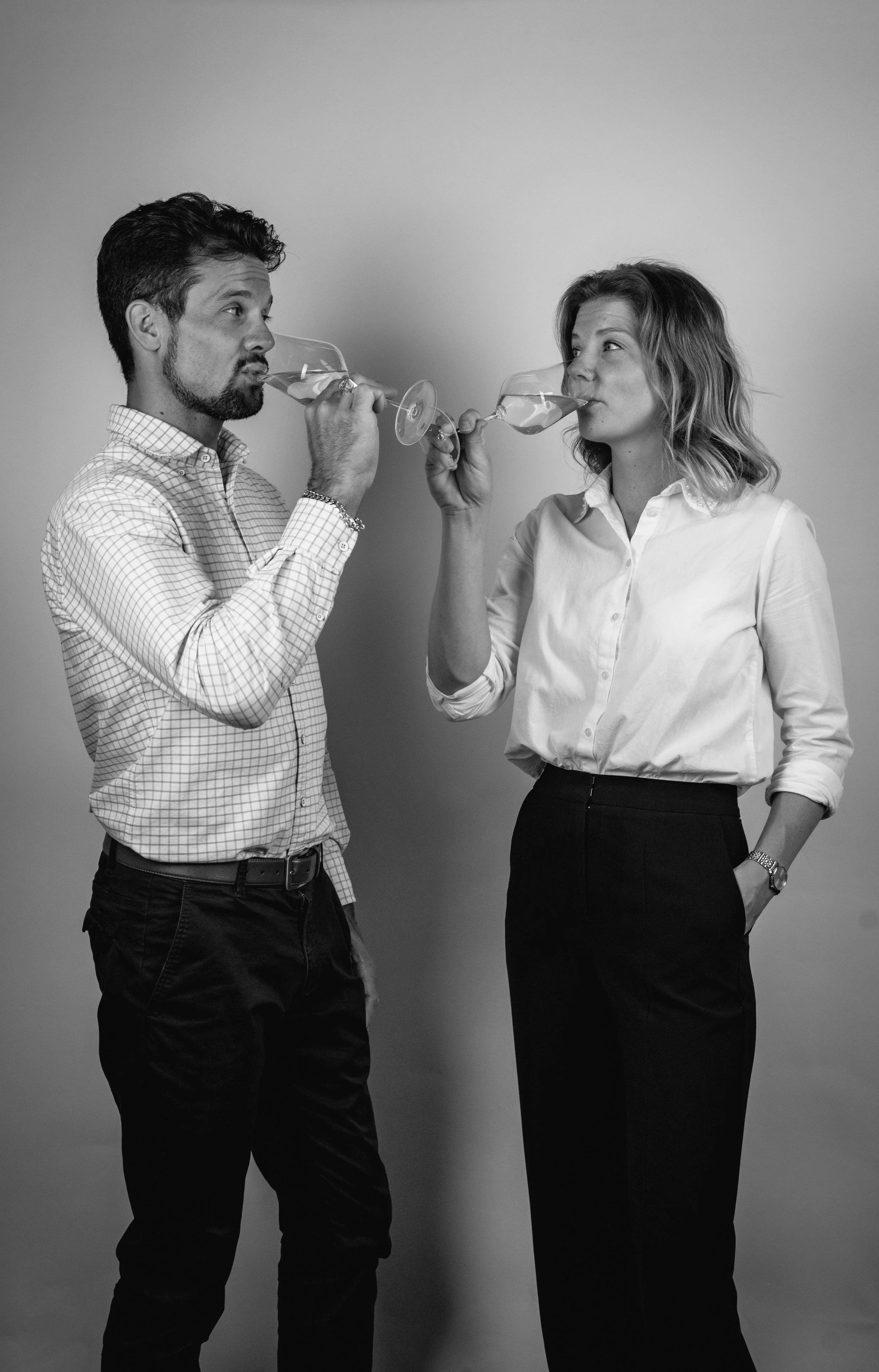 Black and white image of a man and woman drinking from wine glasses.